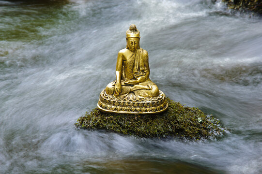  Eine Buddha Skulptur sitzt am flie&szlig;enden Wasser