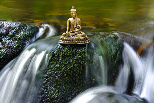 Eine Buddha Skulptur sitzt am flie&szlig;enden Wasser
