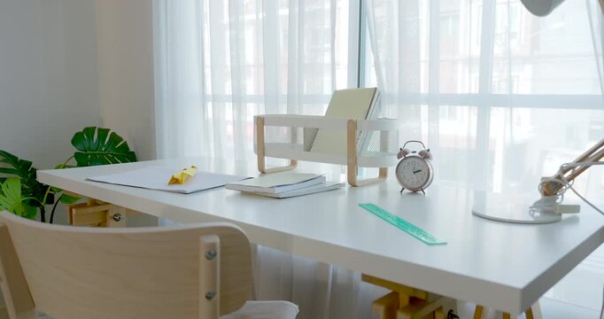 Camera moves across modern child study table with open notebook, pencil, clock, lamp, and chair, suggesting single mother preschool learning routine, creative playtime, indoor family care moment.