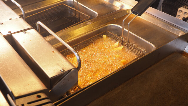Cooking potatoes in hot oil at a diner kitchen