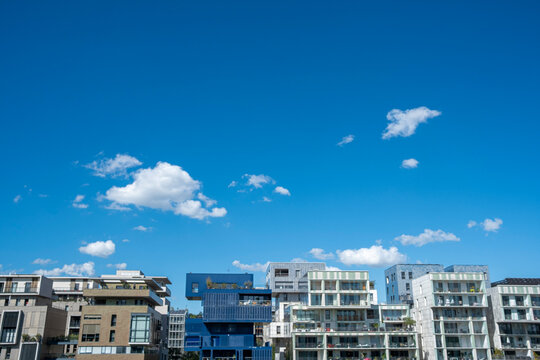 Wide skyline in La Confluence, Lyon, France stretches beneath blue sky, where modern buildings and clouds define waterfront urban architecture