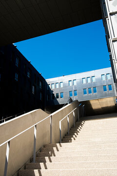 Stairway in La Confluence, Lyon, France climbs between shadow and blue sky, leading through contemporary architecture toward a bright facade