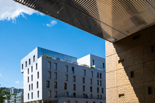 White building in La Confluence, Lyon, France sits below a wooden canopy, where shadow, sky, and facade lines define urban architecture