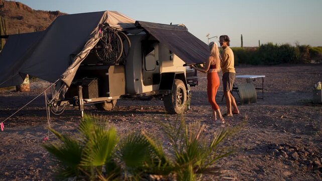 Time lapse of couple seting up awning on their teardrop camper as the sun rises over the beach in Baja, Mexico
