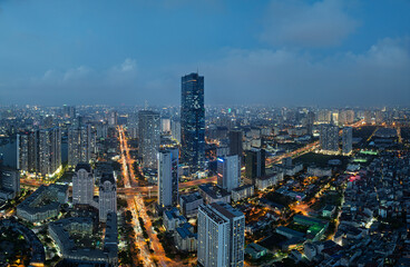 Obraz premium Blue hour panorama of Pham Hung Me Tri intersection surrounded by illuminated modern skyline in Hanoi Vietnam.