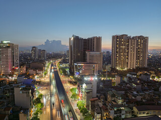 Naklejka premium Twilight cityscape of Minh Khai road with illuminated traffic trails and modern residential towers in Hai Ba Trung district Hanoi.
