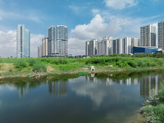 Fototapeta premium Daytime view of modern apartment buildings reflected in calm water near Ngoai Giao Doan urban area west of West Lake Hanoi.