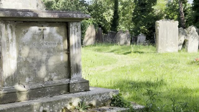 Ancient stone gravestones in green churchyard panning