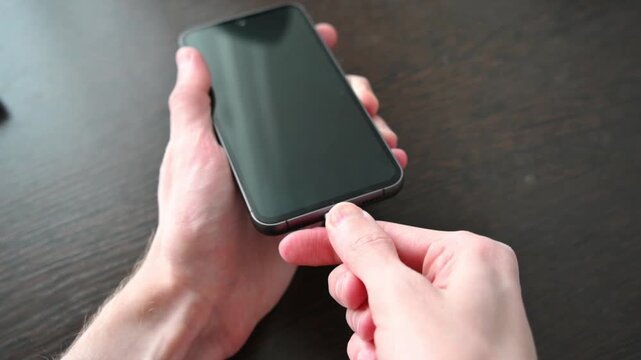 Hands plugging white usb c cable into smartphone showing battery charging screen