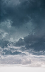 Obraz premium Moody vertical storm clouds and dark dramatic sky. Dramatic vertical view of dark, ominous storm clouds gathering in a moody sky - abstract weather background.