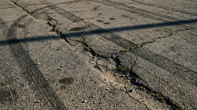 Close-up of cracked and weathered asphalt road surface with rough texture