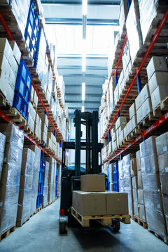 Warehouse Aisle with Forklift, Industrial Shelving, and Stacked Crates and Boxes.