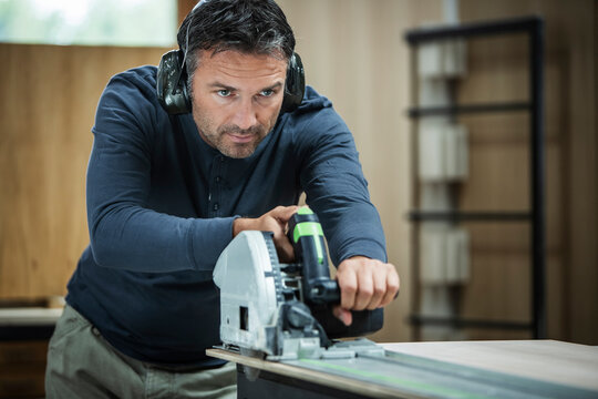Carpenter Measuring, Cutting, and Assembling Wood in a Workshop