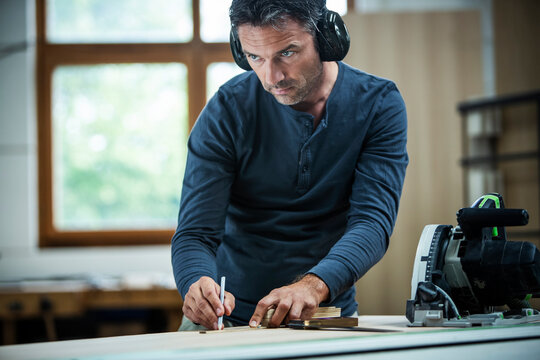 Carpenter Measuring, Cutting, and Assembling Wood in a Workshop