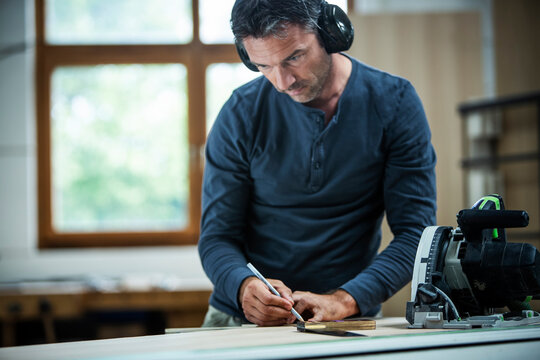 Carpenter Measuring, Cutting, and Assembling Wood in a Workshop