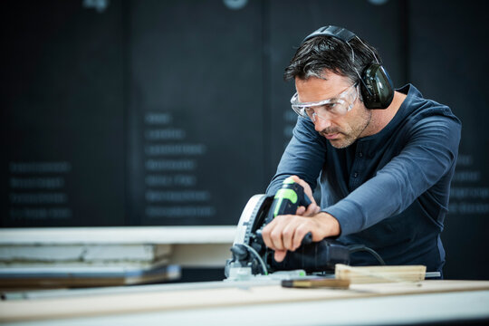 Carpenter Measuring, Cutting, and Assembling Wood in a Workshop