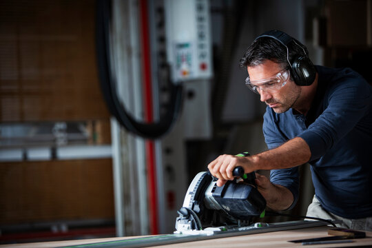 Man cutting wood with track saw in a wood working shop