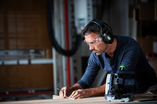 Man cutting wood with track saw in a wood working shop