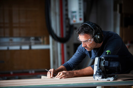 Man cutting wood with track saw in a wood working shop
