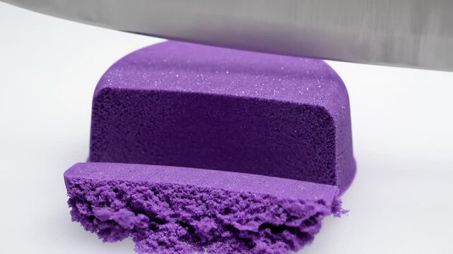 Purple sponge being cut by knife symbolizing conceptual art and dynamic energy