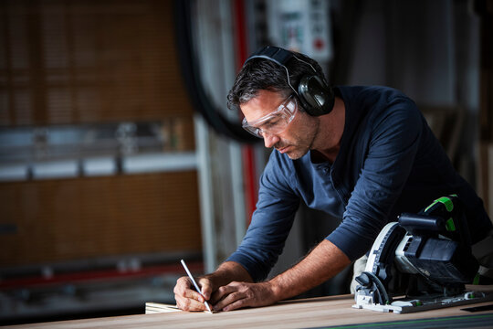 Man cutting wood with track saw in a wood working shop