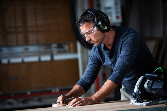 Man cutting wood with track saw in a wood working shop
