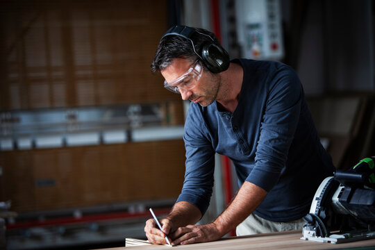 Man cutting wood with track saw in a wood working shop