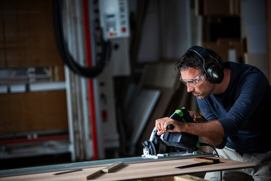 Man cutting wood with track saw in a wood working shop