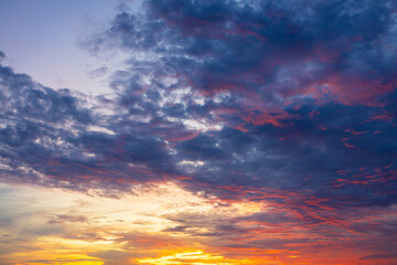 Fototapeta premium Dramatic golden hour sky with colorful sunset clouds,A breathtaking panoramic view of a dramatic golden hour sky, featuring vibrant orange, pink, and purple sunset clouds scattered across a deep blue 