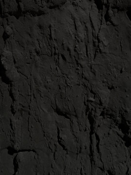 Close-up of a black graphite wall with an embossed raised surface. Dark textured material with pronounced depth.