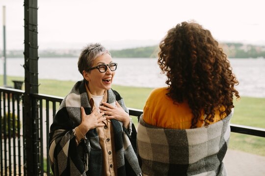 Generational women laughing together wrapped in plaid blankets