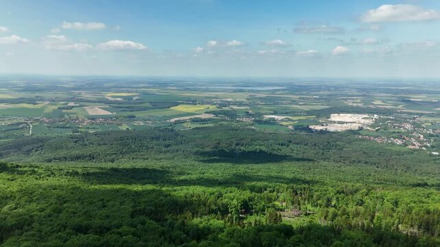 Aerial view of vast forest and farmland plain stretching to the horizon under a blue sky in summer