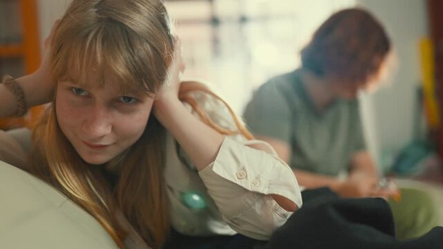 Frustrated teenage daughter covering ears while mother talks