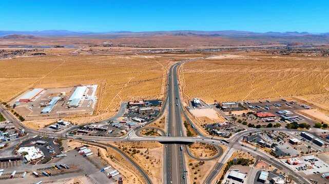 Vast arid desert with modern cityscape and developed road infrastructure. Approaching the intersection on the highways with transport moving by.