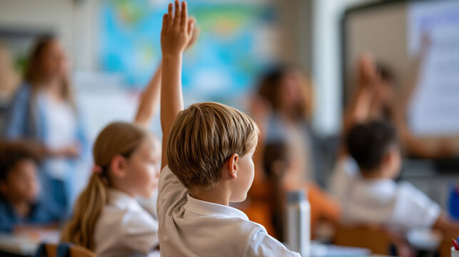 Environmental science lesson primary school children raising hands, female teacher calling boy and girl to board for presenting homework on renewable energy in front of class,