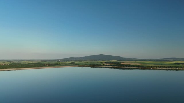 Aerial View of Calm Lake with Forest Shoreline and Mountains at Sunset in Poland