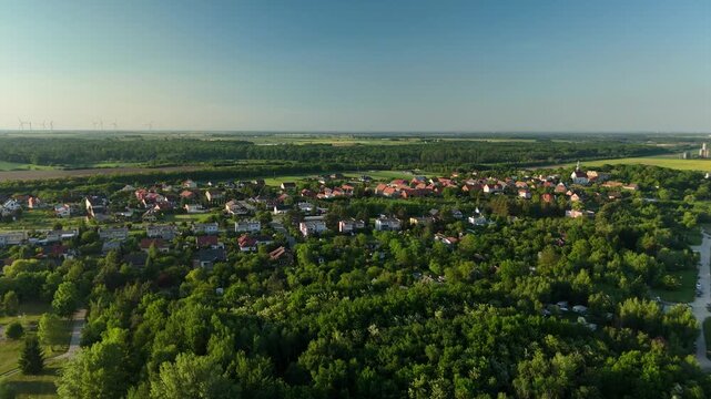 Aerial view of a village with houses surrounded by forest and farmland on a flat plain in Poland in summer