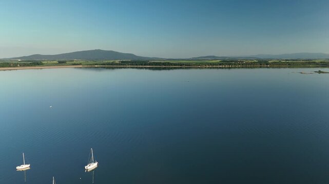 Aerial View of Calm Lake with Forest Shoreline and Mountains at Sunset in Poland
