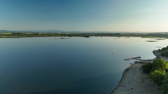 Aerial View of Calm Lake with Forest Shoreline and Mountains at Sunset in Poland