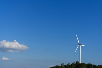 Obraz premium Wind turbine for renewable energy on a hill under a beautiful clear blue sky.