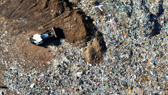 Aerial view of a bulldozer working on a large landfill site with piles of waste and brown earth Vaalwater, Limpopo, South Africa.