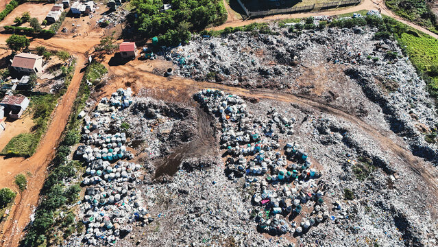Aerial view of a large landfill site with piles of waste bags and dirt tracks near a rural settlement Vaalwater, Limpopo, South Africa.