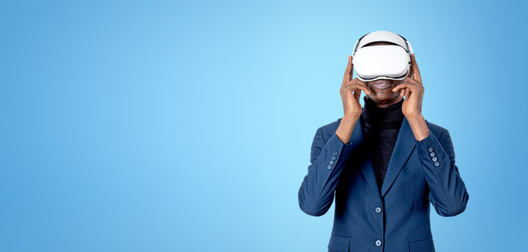 A person wearing vr headset in business clothing on a blue background, showing concept of virtual reality, innovation, technology and immersive experience