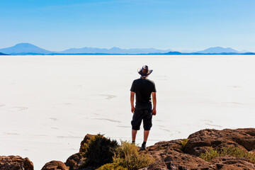 Fototapeta premium A man admiring the magnificent natural scenery of the Salar de Uyuni on Incahuasi Island, Bolivia.