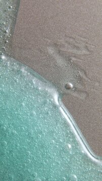 Blue cream liquid gel serum flowing down on silver texture, makeup and cosmetics background, skincare or hair product