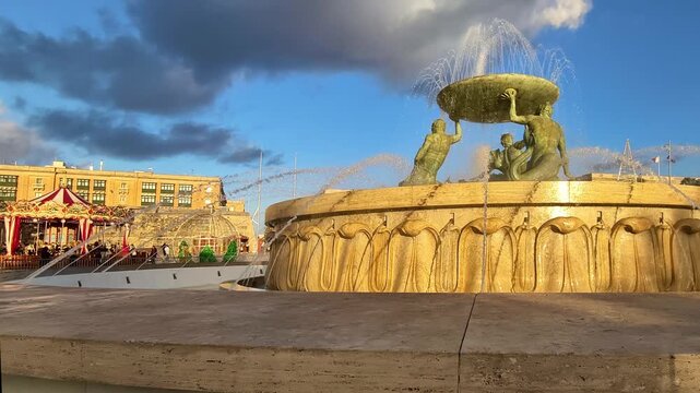 Valletta, Malta, Triton Fountain in front of Christmas attractions and historic buildings at warm evening light