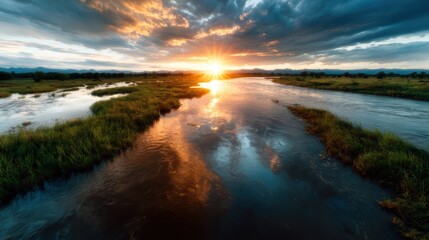 Obraz premium This serene landscape captures a breathtaking sunset reflecting on a calm river, framed by lush grass, evoking tranquility and inspiring inspiration in nature lovers.