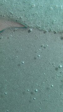 Blue cream liquid gel serum flowing down on silver texture, makeup and cosmetics background, skincare or hair product