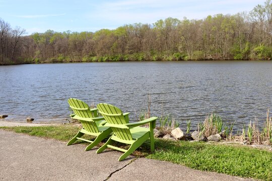 The green chairs at the lake in the park on a sunny day.