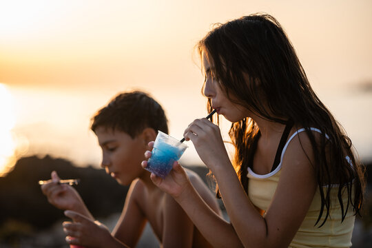 Children drinking colorful slushie during summer sunset